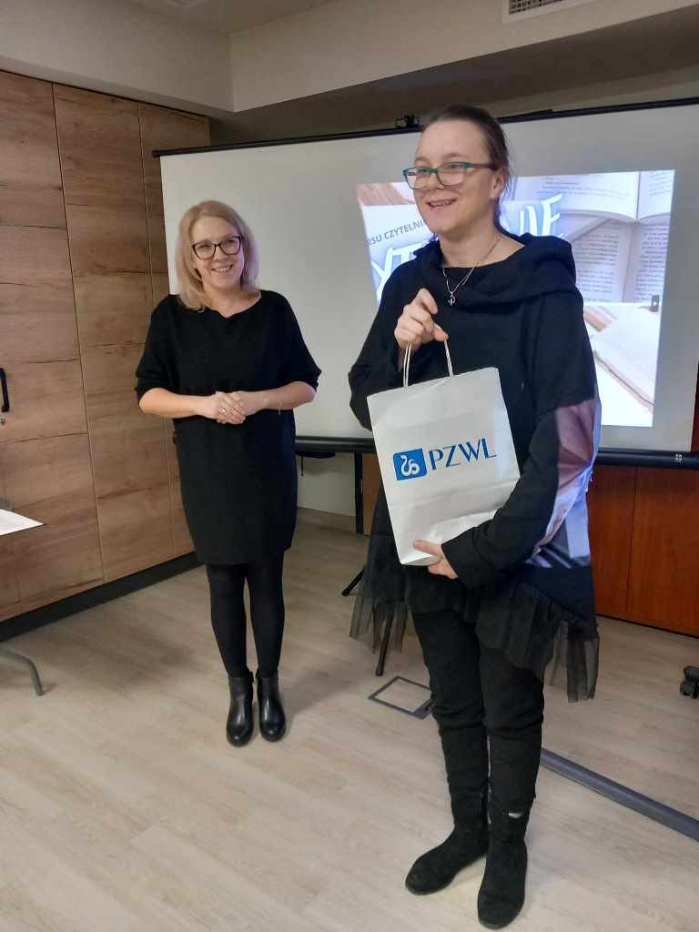 Kobieta wręcza nagrodę uczestnikowi konkursu